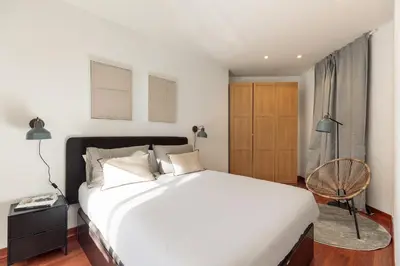 a bedroom with a large white bed and a chair at Enjoy Apartments Urban Retreat Valencia 3 in Barcelona