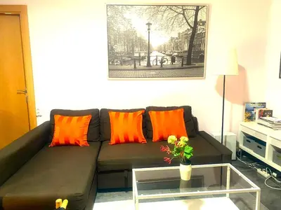 a living room with a brown couch with orange pillows at L5 Metro Stadium Home in Hospitalet de Llobregat