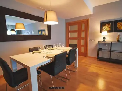 a dining room with a white table and black chairs at Alcam Cervantes Playa Badalona in Badalona