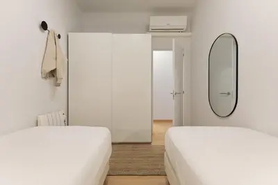 two beds in a white room with a mirror at Enjoy Apartments Ecuador in Barcelona