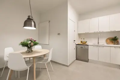 a kitchen and dining room with a table and white cabinets at Enjoy Apartments Ecuador in Barcelona