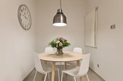 a dining room table with white chairs and a vase of flowers at Enjoy Apartments Ecuador in Barcelona