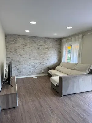 a bedroom with two beds and a tv and a brick wall at Caldetas relax apartment in Sant Vicenç de Montalt