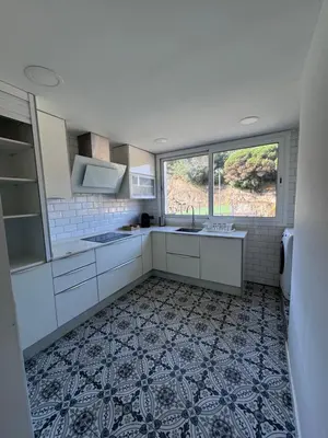 a kitchen with white cabinets and a tile floor at Caldetas relax apartment in Sant Vicenç de Montalt