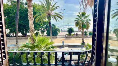 a balcony with a view of the beach and palm trees at Sitges Seafront BATLLÓ in Sitges