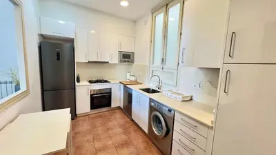a kitchen with white cabinets and a stainless steel refrigerator at Sitges Seafront BATLLÓ in Sitges