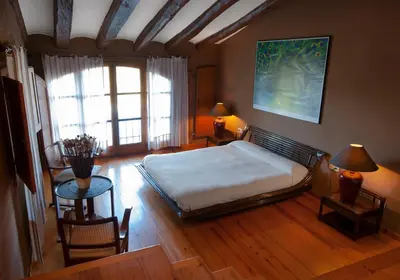 a bedroom with a bed and a table and chairs at Can Julià de Masia Olivera in Subirats