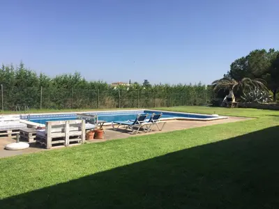 a swimming pool with two chairs and a table at Can Julià de Masia Olivera in Subirats