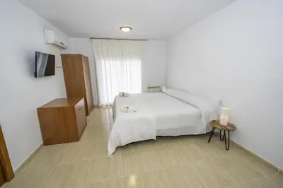 a bedroom with a white bed and a television at HomeHolidaysRentals Belisa - Costa Barcelona in Pineda de Mar