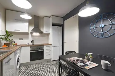 a kitchen with a table and a clock on the wall at Spacious 3BRapartment in PobleSec with balcony in Barcelona