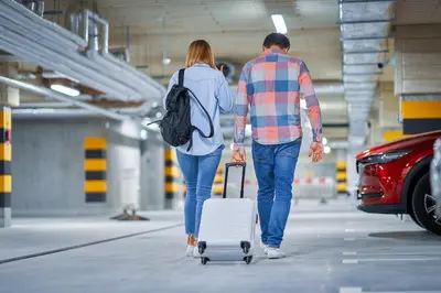 a man and woman walking with a suitcase and a car at Sercotel Barcelona El Prat in El Prat de Llobregat