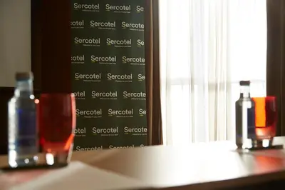 two bottles of wine sitting on a table next to a window at Sercotel Barcelona El Prat in El Prat de Llobregat