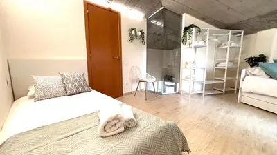 a bedroom with a white bed and a room with a ladder at Dúplex ático familiar by Prestigi in Terrassa