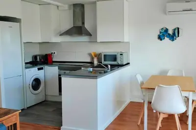 a kitchen with white cabinets and a table and a microwave at Apartamento con vista al mar in Vilanova i la Geltrú