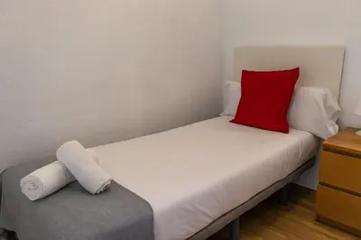 a bed with a red pillow on top of it at Apartments BCN Central-Colon in Barcelona