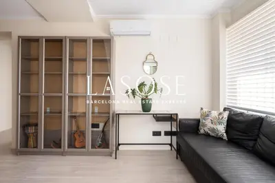 a living room with a black couch and a book shelf at Vacation house with garden in the foothills in Barcelona