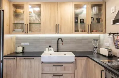 a kitchen with wooden cabinets and a white sink at Hogar con encanto y personalidad in L'Ametlla del Vallès
