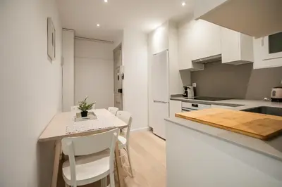 a kitchen with white cabinets and a table and chairs at E4lle1031 - Studio next to Plaza Espanya in Barcelona