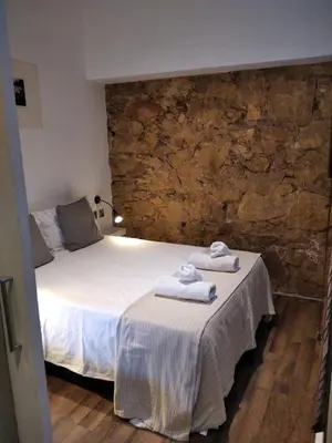 a bedroom with a bed and a stone wall at ApartEasy - MONUMENT, large, cosy apartment in Barcelona
