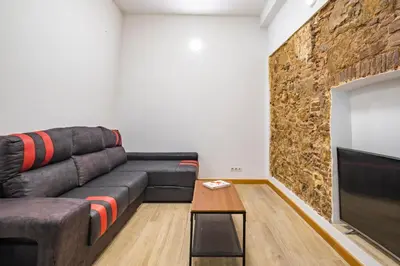 a living room with a couch and a television at BRAND NEW Pl Espana Sants Fira Apartment 2024 Built, Aplus, AirCon & Heating, Gigabit WiFi, Parking in Barcelona