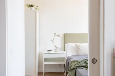 a white bedroom with a bed and a mirror at Modern 1 bedroom apartments near Parallel in Barcelona