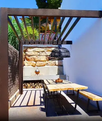 a table and chairs on a patio with a stone wall at Holiday Home Alexander Plana in Pallejá