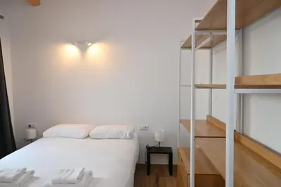 a bedroom with a white bed and a ladder at Homenfun Dalt Badalona in Badalona