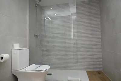 a bathroom with a toilet and a glass shower at Homenfun Dalt Badalona in Badalona
