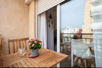 a wooden table with a vase of flowers on a balcony at 2 Habitaciones Hospitalet in Hospitalet de Llobregat