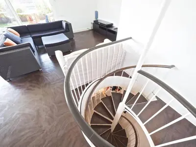 a spiral staircase in a living room with a couch at BCN | Duplex Penthouse & Pool in Sant Andreu de Llavaneres