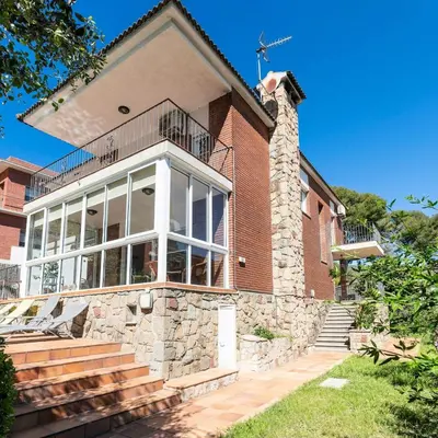 a brick house with large windows and a balcony at Elis house Piscina Privada Villa Mediterránea in Castelldefels