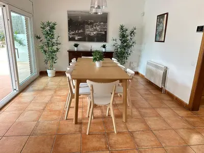 a dining room with a wooden table and white chairs at Elis house Piscina Privada Villa Mediterránea in Castelldefels