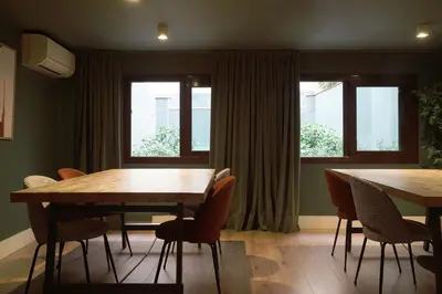 a dining room with two tables and chairs and windows at Numa Barcelona Brio in Barcelona