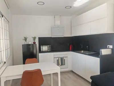 a kitchen with white cabinets and a white table and chairs at Apartamento con vistas al mar in Viladecáns
