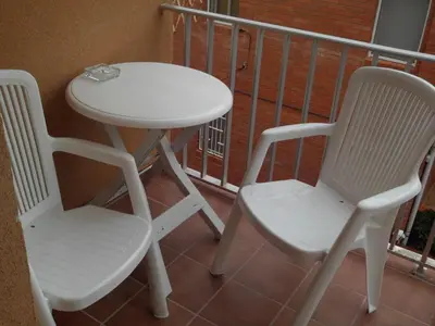 two chairs and a white table and chairs on a balcony at Hostal Cubelles in Cubelles