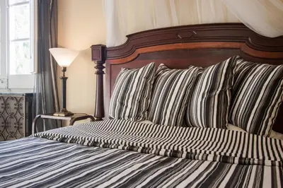 a bed with striped pillows and a wooden head board at Romantisches Fischerhaus am Meer, 200 m vom Strand, Barcelona in Premiá de Mar