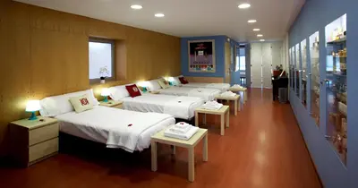 a row of beds in a room with tables at Apartamento Granollers in Granollers