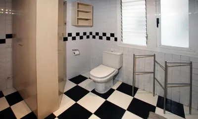 a bathroom with a toilet and black and white checkered floor at Apartamento Granollers in Granollers