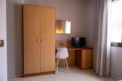 a wooden cabinet next to a desk with a television at Hotel Sant Celoni in San Celoni