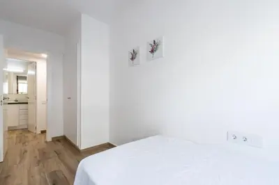 a white room with a bed and a kitchen at Macu in Sabadell