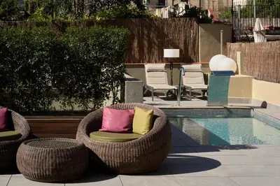 two wicker chairs with pillows sitting next to a pool at Catalonia Port in Barcelona