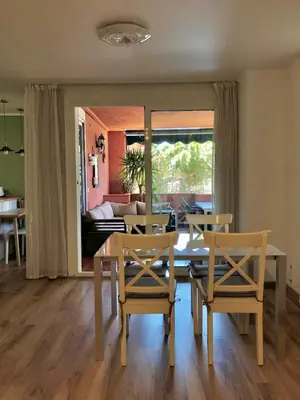 a dining room with a table and chairs and a living room at Beach apartment 2 terraces with parking in Castelldefels