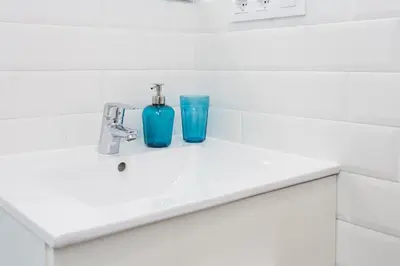 a bathroom sink with a blue bottle and a glass at Opening Doors Sagrada Familia II in Barcelona