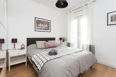 a white bedroom with a large bed and a desk at Opening Doors Sagrada Familia II in Barcelona