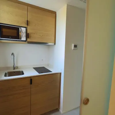 a small kitchen with a sink and a microwave at MYO Barcelona Hotel & Apartments in Castelldefels