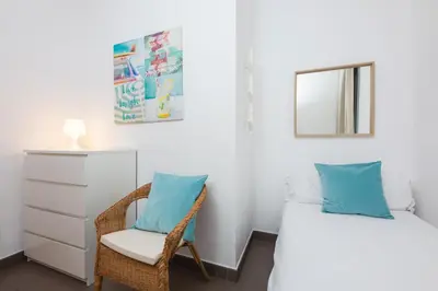 a bedroom with a bed and a chair and a mirror at Apartamentos Cornellalux in Cornellà de Llobregat