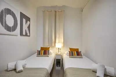 two beds in a room with white walls at BBarcelona Gracia Apartment in Barcelona