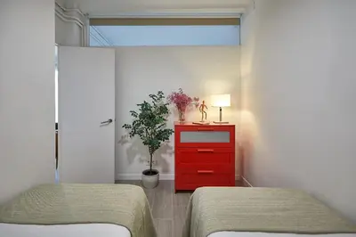 a bedroom with two beds and a red dresser with a plant at BBarcelona Gracia Apartment in Barcelona