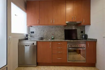 a kitchen with wooden cabinets and a stainless steel oven at Sagrada Familia views, big and bright apartment in Barcelona