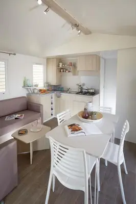 a kitchen with a white table and chairs in a room at Camping Victoria in Canet de Mar
